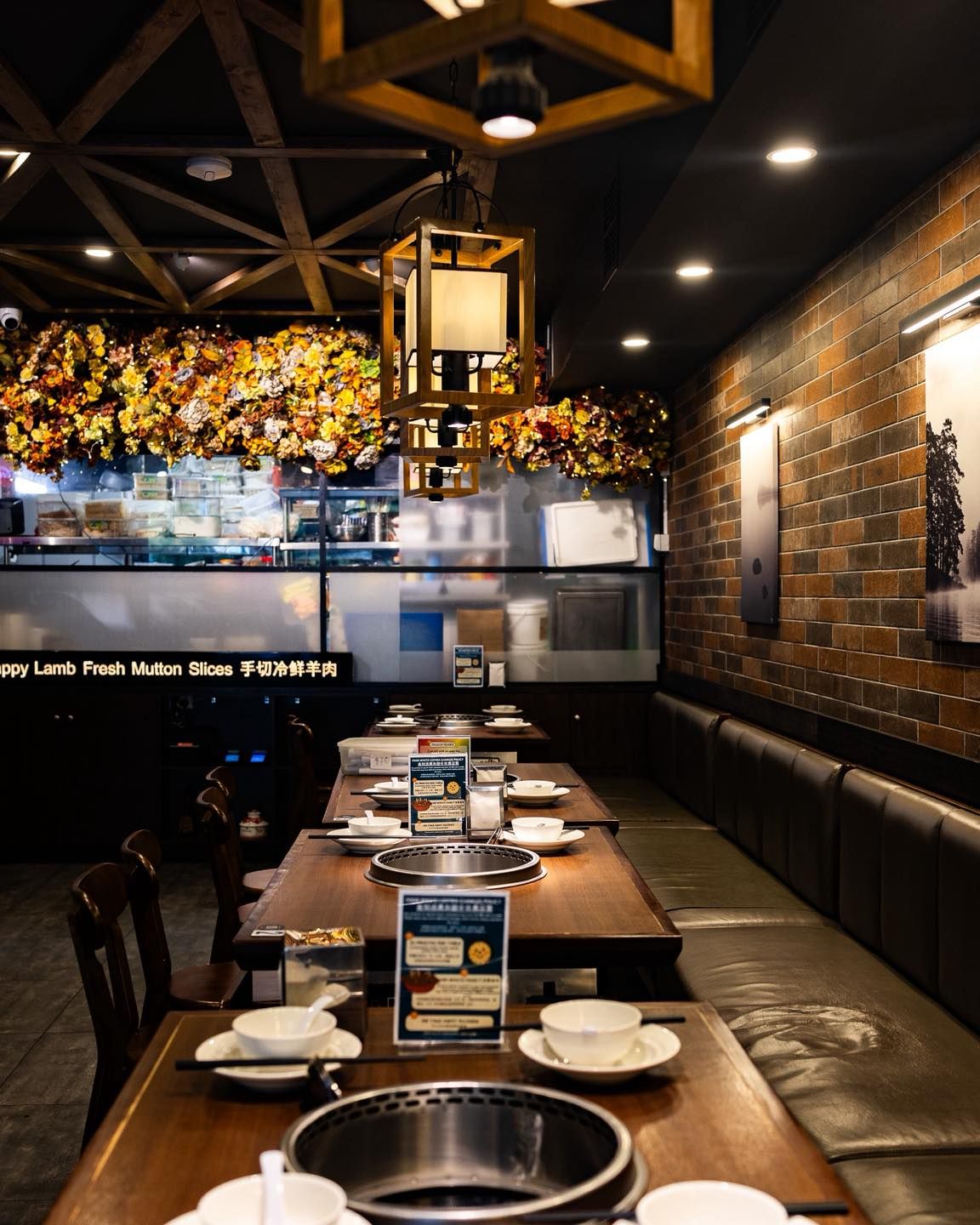 Long hot pot tables with banquette seating under lanterns and a ceiling of dried flowers
